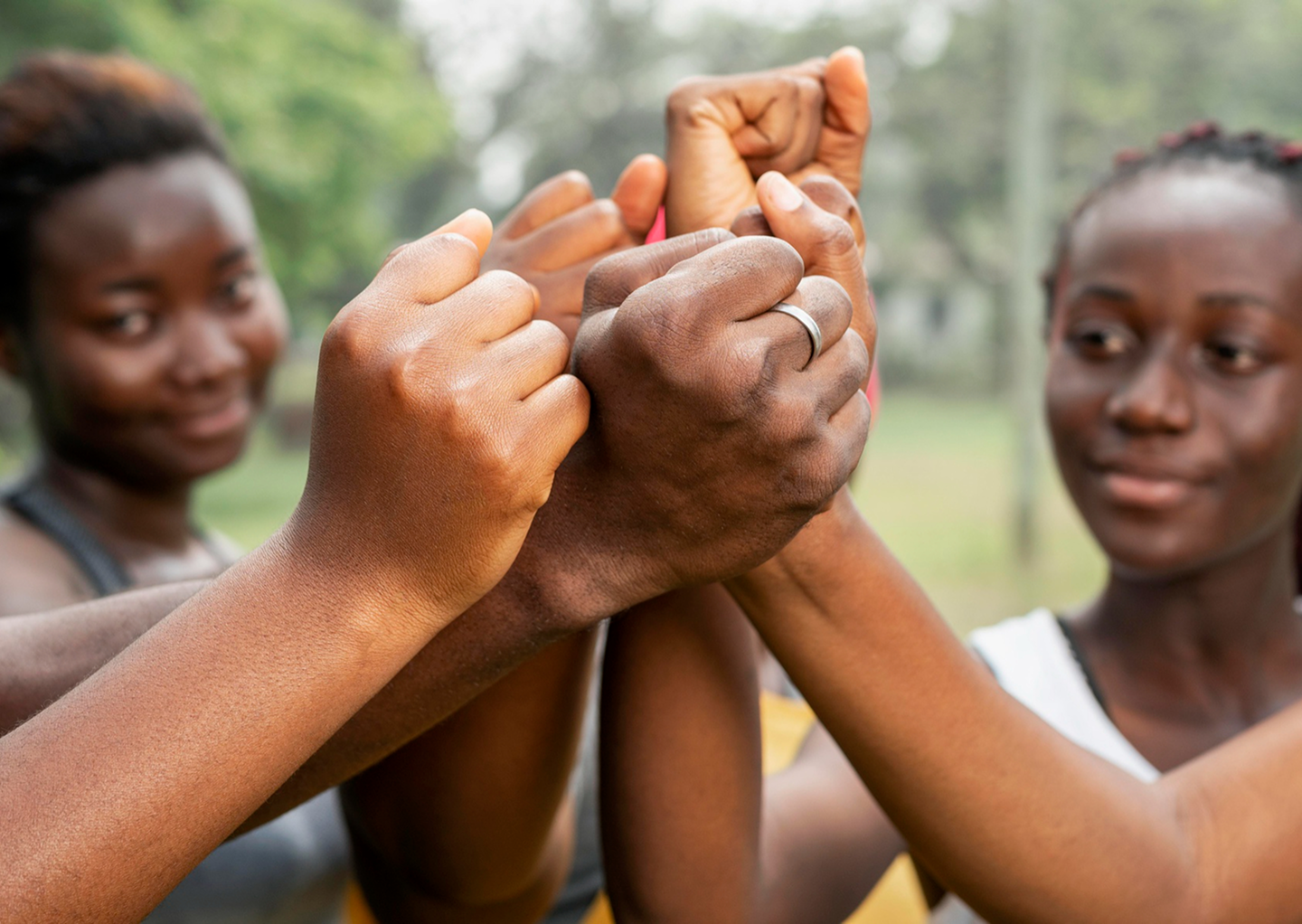 A group of hands together in a circle, symbolizing community and commitment.
